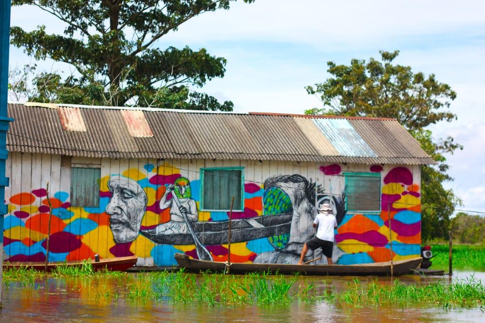 Artistas criam mural em palafitas apoiados em canoas